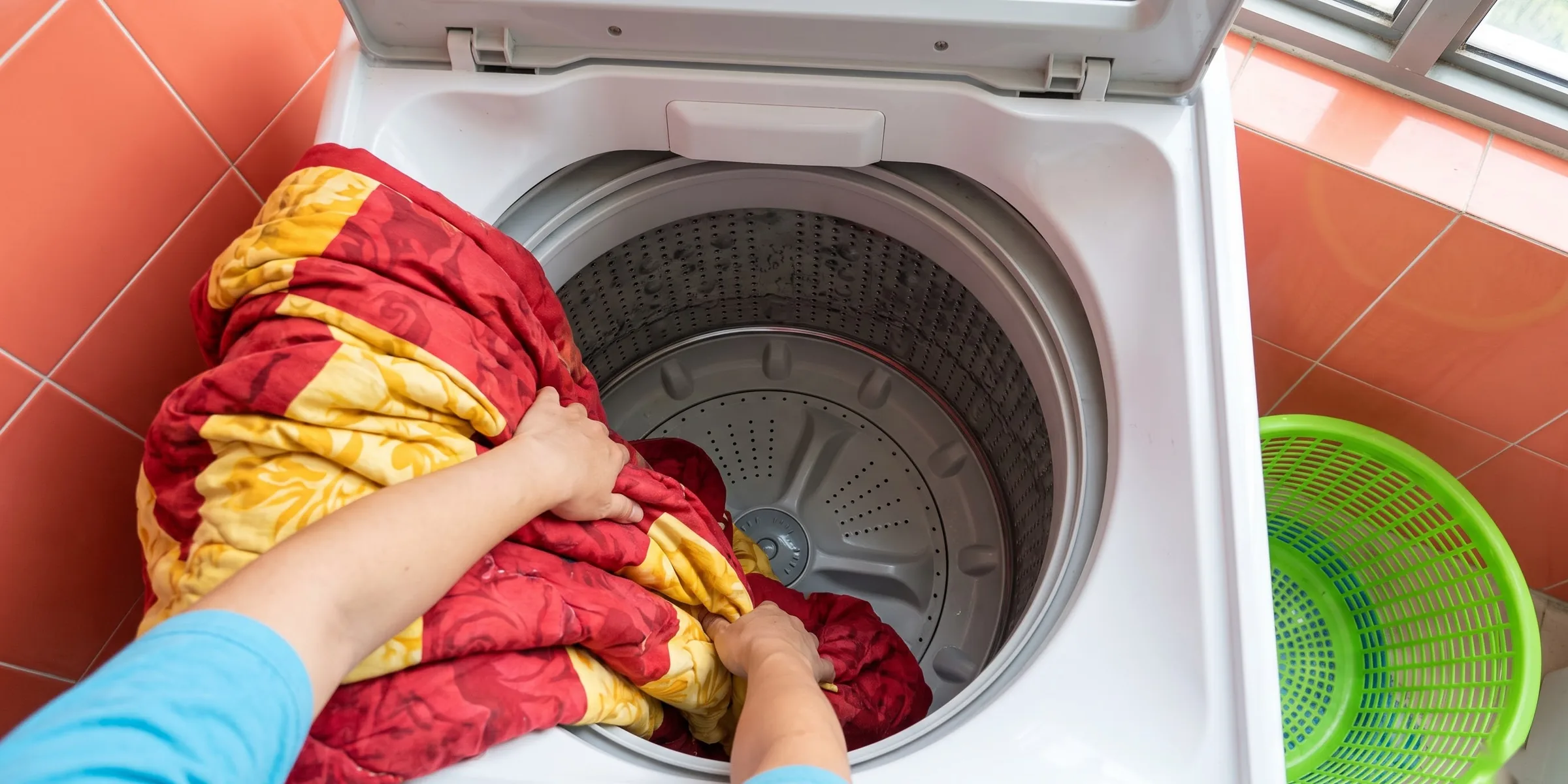 Gỡ chiếc chăn ướt đang vón về một phía, dàn đều quanh mâm giặt máy cửa trên